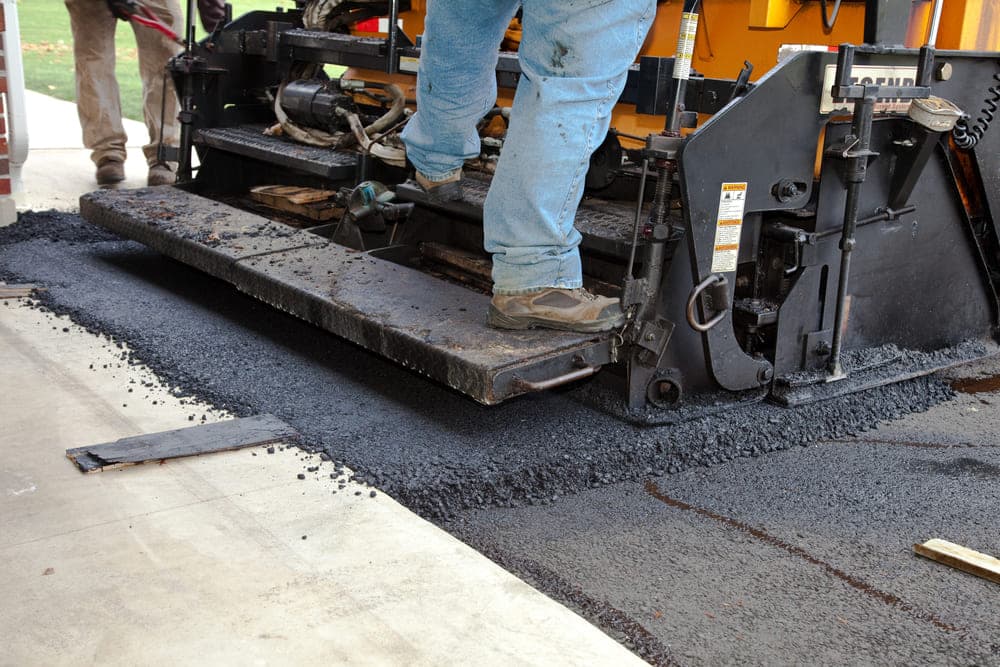 Asphalt repair crew applying fresh mix to a Texas roadway.